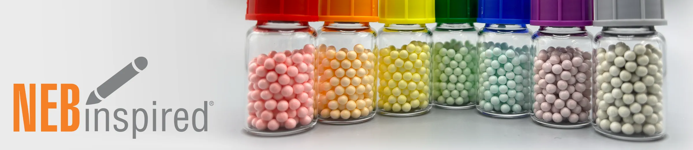 Rainbow-colored vials of lyophilzed beads (lyo beads), with NEB logo
