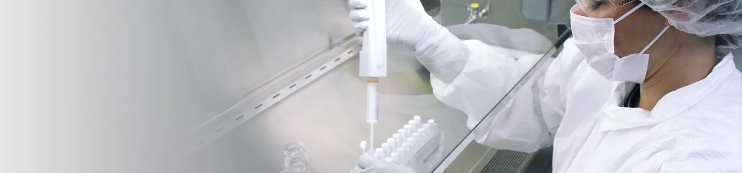 Scientist wearing protective gear under hood with pipette