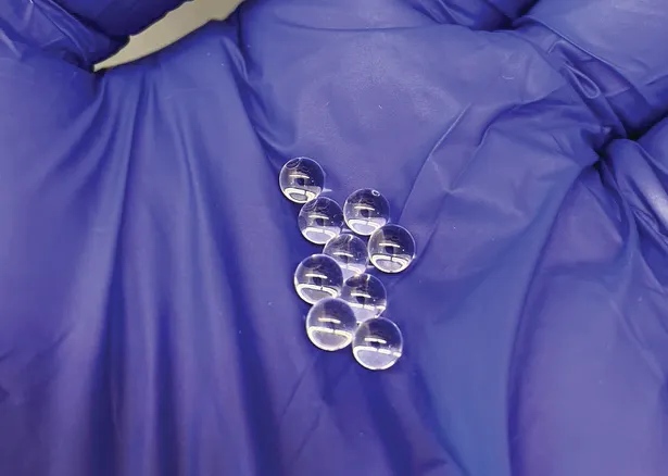 Photo of a gloved hand holding HMW glass beads
