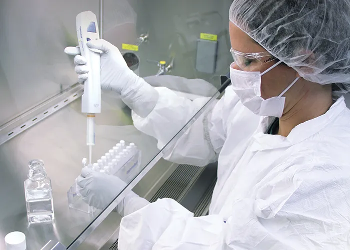 Photo of laboratory technician with pipette in laboratory hood 